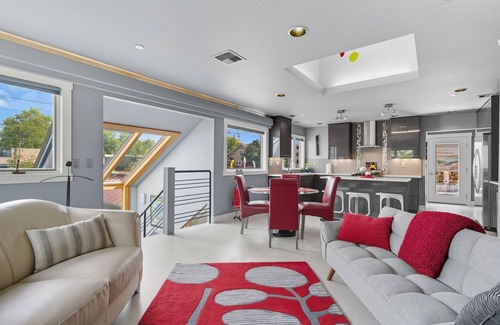 Hough Apartment | Top-level duplex featuring a sleek open concept kitchen with stainless appliances, cozy fireplace, stylish furnishings, and in-unit washer/dryer. Designed for basking in the sun under skylights in thoughtful details throughout.