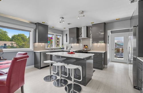 Hough Apartment | Top-level duplex featuring a sleek open concept kitchen with stainless appliances, cozy fireplace, stylish furnishings, and in-unit washer/dryer. Designed for basking in the sun under skylights in thoughtful details throughout.